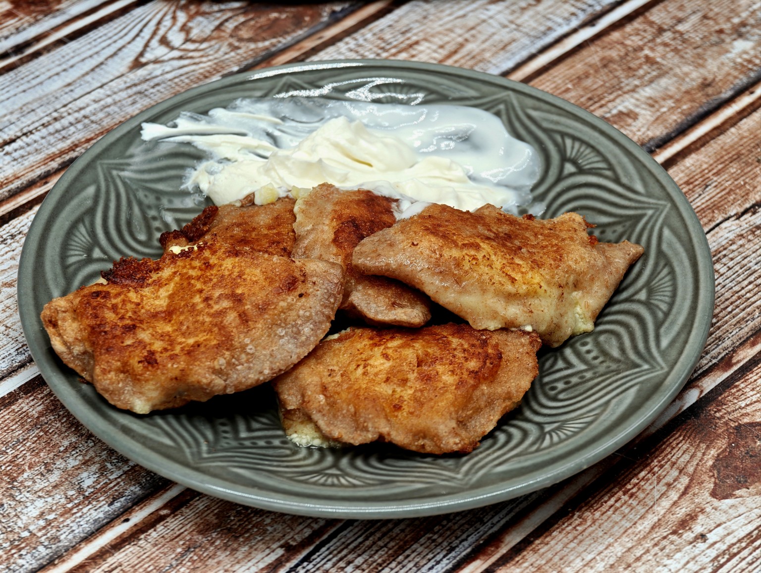 Domowe pierogi ruskie Justyny na zielonym talerzu z jogurtem naturalnym; sałatka jest dodatkiem w przepisie, nie ma jej na oryginalnym zdjęciu